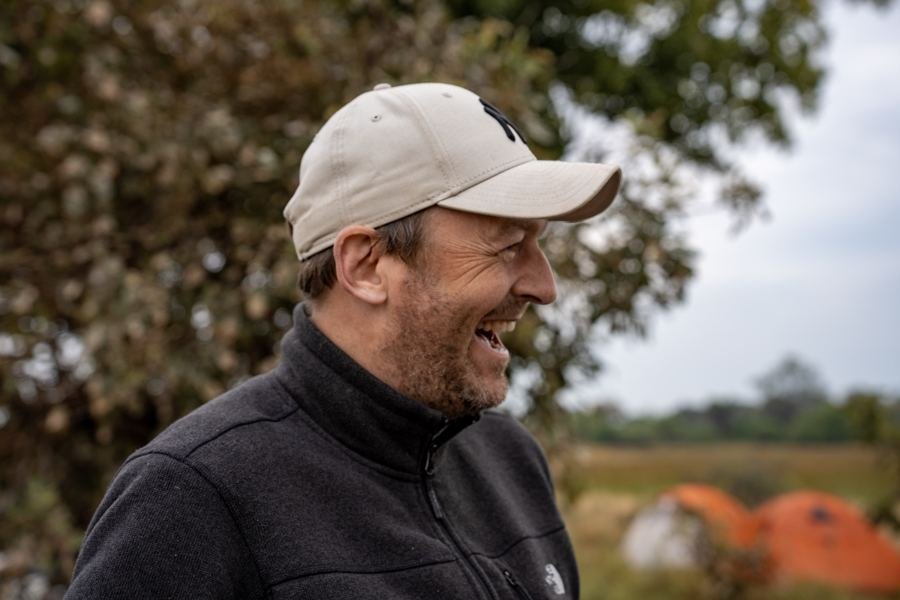 A participant laughing, tents in the background